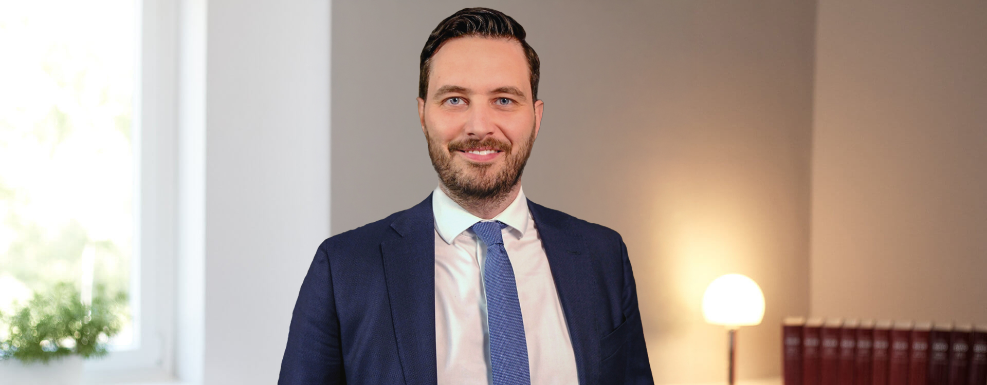Dr. Frédéric Schneider, Strafverteidiger und Partner bei SCHNEIDER || MICK, im hellen Kanzleibüro mit Bücherregal